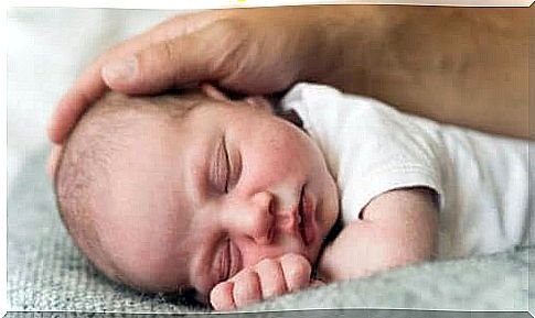 Baby sleeps with parent's hand on head