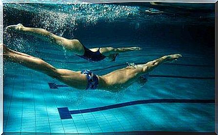 Two people are swimming together under water