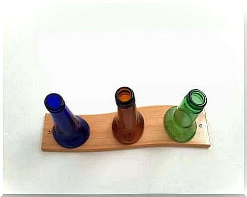 Three bottles on a board make up a homemade coat rack