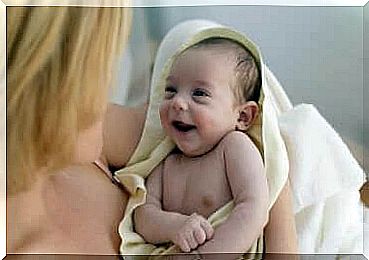 Mom hugs smiling baby in towel