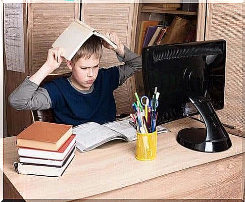 Angry boy with books at computer