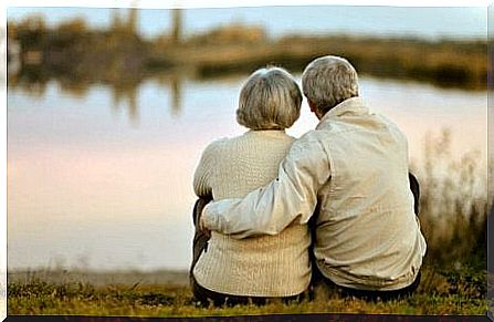 older couple hugging each other and looking out over lake